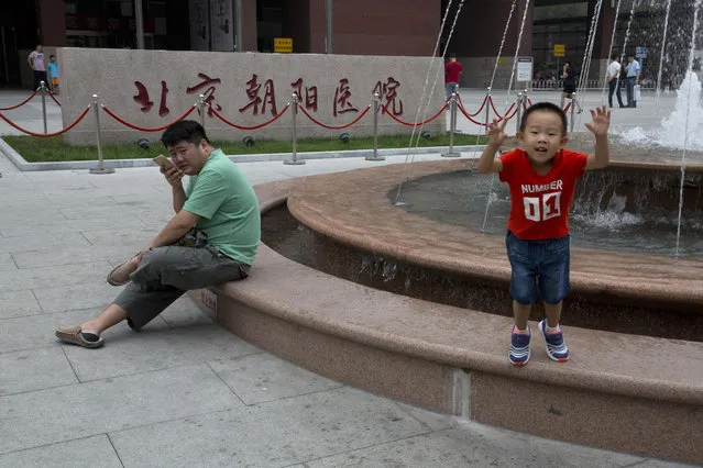 In this photo taken Wednesday, August 24, 2016,  a child jumps from a fountain near the sign for Beijing Chaoyang Hospital, one of the hospitals approved for organ transplants, in Beijing, China. China claims it ended the harvesting of executed inmates' organs for transplants in January 2015. Some foreign doctors who have worked in China say authorities are behaving more responsibly, but other observers say China hasn't done enough to prove that it's fulfilled that pledge. (Photo by Ng Han Guan/AP Photo)