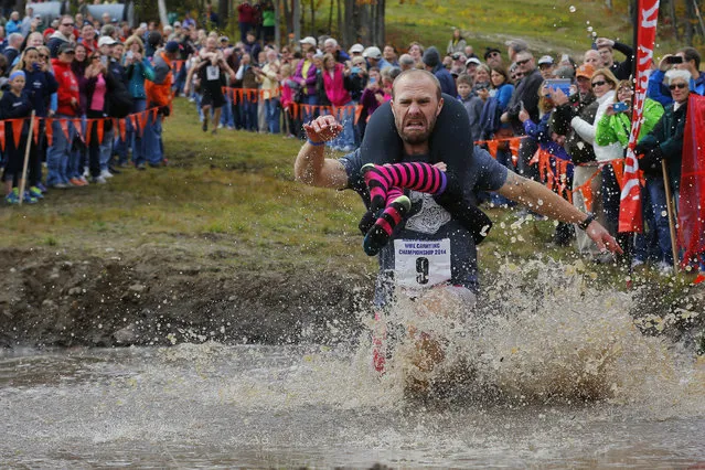 Eventual winners Jesse Wall carries Christina Arsenault through the water pit while competing in the North American Wife Carrying Championship at Sunday River ski resort in Newry, Maine October 11, 2014. (Photo by Brian Snyder/Reuters)