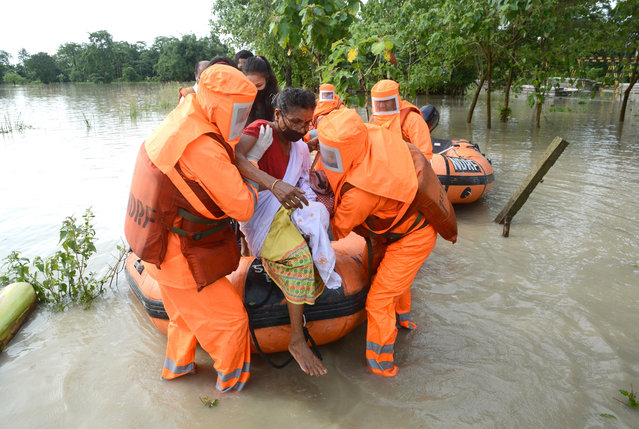 National Disaster Response Force (NDRF) personnel wearing protective equipment rescue a woman from the flood affected village at Pathsala in Barpeta district of Assam, India, 12 July 2020. Heavy rainfall during the past days has flooded many villages in the state, leaving over half million people affected by it with rising water level in river Brahmaputra and its tributaries. (Photo by EPA/EFE/Stringer)