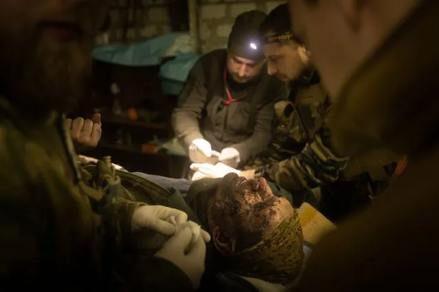 Military medics work on a member of the Ukrainian military suffering from head and leg injuries caused by a mine, in a frontline field hospital on December 04, 2022 outside Bakhmut, Ukraine. Russia continues its campaign to seize Bakhmut, Donetsk region, in what many analysts regard as an offensive with more symbolic value than operational importance for Russia. In a recent intelligence report, the British ministry of defense said Russia would try to encircle the city. (Photo by Chris McGrath/Getty Images)