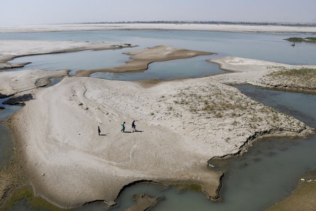 People walk on the dry patch of the Indus River, in Jamshoro, Pakistan on March 15, 2025. (Photo by Yasir Rajput/Reuters)