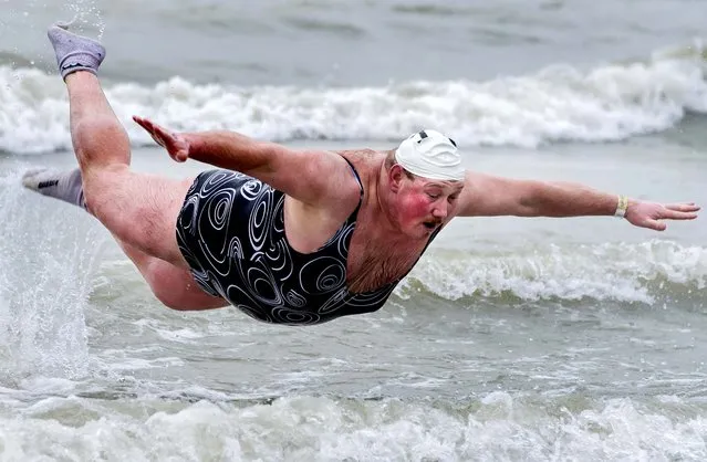 With temperatures around 46 degrees Fahrenheit, a man plays in the surf, joining thousands of others in celebrating the New Year by jumping into the North Sea, during the traditional New Year's Dive in Ostend, Belgium, on January 5, 2013. (Photo by Geert Vanden Wijngaert/Associated Press)