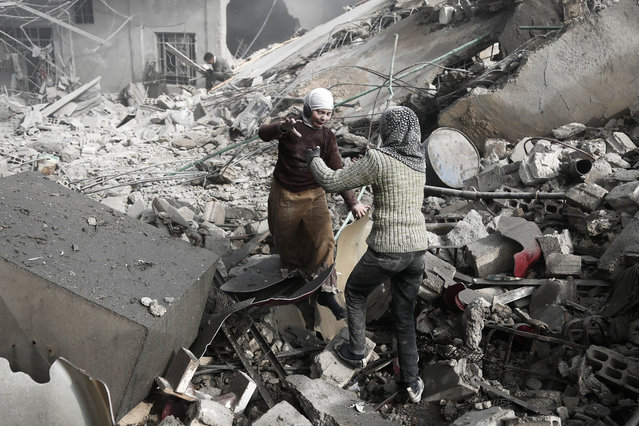 Two Syrian sisters run across the rubble to embrace after finding each other alive following an air strike on Hamouria, in the besieged rebel-held Eastern Ghouta area near Damascus, on January 9, 2018. Air strikes and artillery fire killed dozens of civilians in the besieged rebel enclave near Damascus targeted by near-daily regime bombardment, a war monitor said. (Photo by Abdulmonam Eassa/AFP Photo)