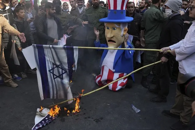 Iranians burn representations of the U.S. and Israeli flags as a man wearing Uncle Sam costume cries during annual demonstration in front of the former U.S. Embassy in Tehran, Iran, Friday, November 4, 2022. (Photo by Vahid Salemi/AP Photo)