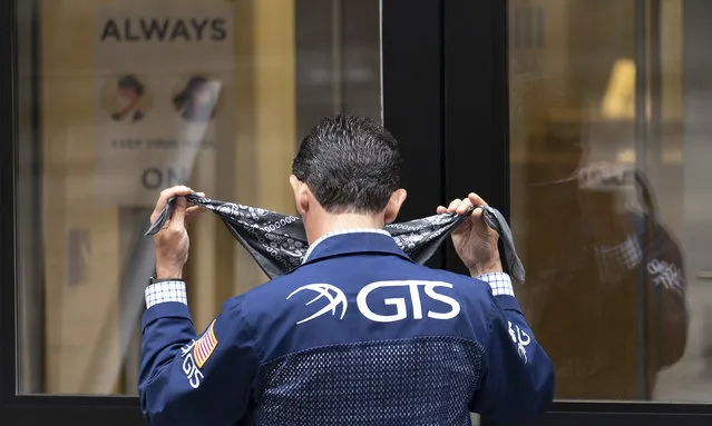 A stock trader puts on his mask before entering the New York Stock Exchange, Monday, August 31, 2020, in New York. (Photo by Mark Lennihan/AP Photo)