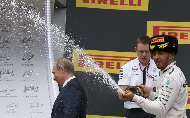 Russian President Vladimir Putin (L) leaves the winners podium as Mercedes Formula One driver Lewis Hamilton of Britain (R) sprays champagne in celebration after winning the Russian F1 Grand Prix in Sochi, Russia, October 11, 2015. (Photo by Grigory Dukor/Reuters)