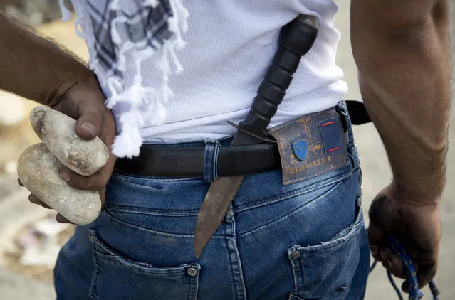 A Palestinian demonstrator has a knife in his belt and rocks in his hand during clashes with Israeli troops, near Ramallah, West Bank, Sunday, October 18, 2015. (Photo by Majdi Mohammed/AP Photo)
