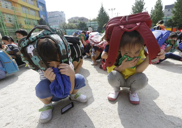 Elementary school students, with schoolbags on their heads, take shelter on the ground during an earthquake drill at Songjung Elementary School in Seoul, South Korea, Friday, September 23, 2016. The drill was held after the country was recently hit by a series of earthquakes. (Photo by Ahn Young-joon/AP Photo)