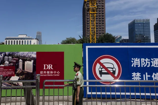 Development is evident throughout Beijing with new towers going up on May 25, 2016. A state security guard mans a gate at a media center. (Photo by Michael Robinson Chavez/The Washington Post)