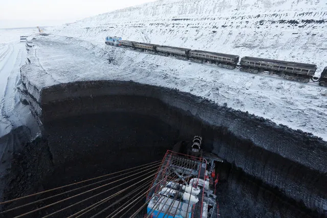 A coal-train moves along coal beds, as a rotary dredge excavates coal at Russia's largest Borodinsky opencast colliery, owned by the Siberian Coal Energy Company (SUEK), near the Siberian town of Borodino, Krasnoyarsk region, Russia, November 29, 2017. (Photo by Ilya Naymushin/Reuters)