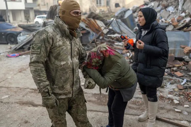 A woman pleads to a Turkish soldier to save her son, next to the rubble of a collapsed building in Hatay, southeastern Turkey, on February 8, 2023, two days after a strong earthquake struck the region. Searchers were still pulling survivors on February 8 from the rubble of the earthquake that killed over 11,200 people in Turkey and Syria, even as the window for rescues narrowed. For two days and nights since the 7.8 magnitude quake, thousands of searchers have worked in freezing temperatures to find those still alive under flattened buildings on either side of the border. (Photo by Bulent Kilic/AFP Photo)