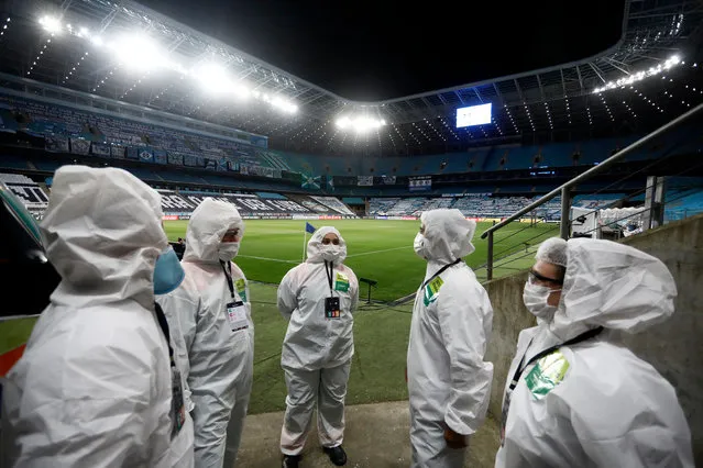 Medical staff wearing PPE gather next to an ambulance at pitch side of an empty Arena Do Gremio due to coronavirus restrictions before a Group E match of Copa CONMEBOL Libertadores 2020 between Gremio and América de Cali aon October 22, 2020 in Porto Alegre, Brazil. (Photo by Diego Vara – Pool/Getty Images)