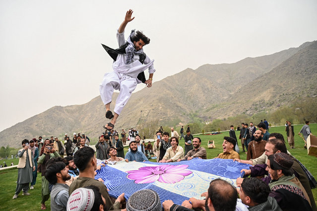 Afghan people throw a man up in the air as they gather for leisure activities on the outskirts of Kabul on April 18, 2025. (Photo by Wakil Kohsar/AFP Photo)