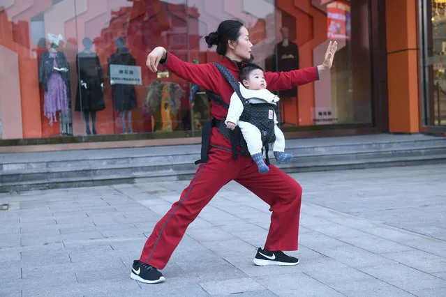 A woman carrying her baby grandson practices Tai Chi at a square on October 19, 2020 in Fuyang, Anhui Province of China. (Photo by Wang Biao/VCG via Getty Images)