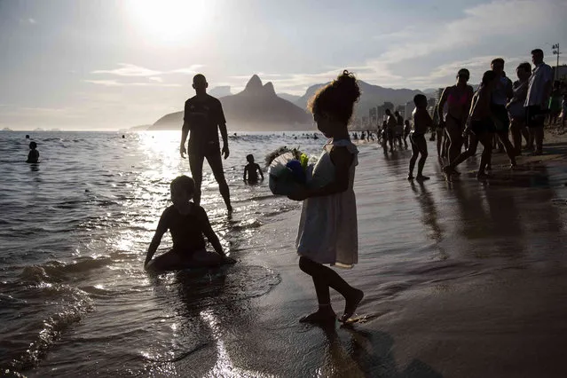A child carries offerings to the goddess of the sea Yemanja in the waters of Arpoador beach during the annual celebration of the deity, in Rio de Janeiro, Brazil, Thursday, February 2, 2023. (Photo by Bruna Prado/AP Photo)