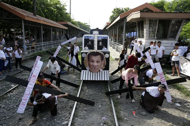 A picture of Philippine President Rodrigo Duterte is seen on a mock train as protesters carrying wooden crosses reenact the sufferings of Jesus Christ during a rally on holy week in Manila, Philippines on Tuesday, March 27, 2018. The group used the demonstration to dramatize the plight of the urban poor under the government of Philippine President Rodrigo Duterte. (Photo by Aaron Favila/AP Photo)