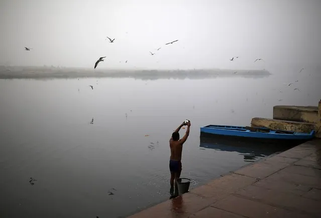 A Hindu devotee prays to the Sun god as he stands in the waters of the river Yamuna on a cold, winter morning in New Delhi December 18, 2014. (Photo by Ahmad Masood/Reuters)