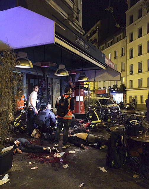 Victims of a shooting attack lay on the pavement outside La Bell Equipe restaurant in Paris Friday, November 13, 2015. Well over 100 people were killed in Paris on Friday night in a series of shooting, explosions. (Photo by Anne Sophie Chaisemartin via AP Photo)