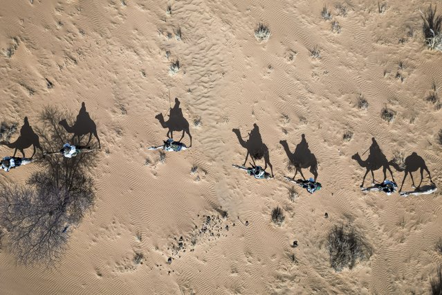 This aerial view shows members of the Mehariste National Guard unit patrolling in the Hodh Ech Chargui region, on April 7, 2025. Heirs of units created under French colonisation, these desert cavalrymen have regained a central role in the security strategy of this predominantly desert West African country. To tame the vast territory that shares 2200km of often porous and poorly defined borders with Mali plagued by a jihadist insurgency, Mauritania has relied on the slow pace of the dromedary where even 4x4s get stuck. The unit was declining a few years ago with only about fifty men due to lack of resources, but since 2019 it has experienced a true revival supported by European Union funding of several million euros. Today, the Nomadic Group consists of about 150 men and a herd of 400 dromedaries. Mauritania has not experienced a jihadist attack since 2011 whereas its neighbour Mali has been mired in conflict for over a decade. (Photo by Patrick Meinhardt/AFP Photo)