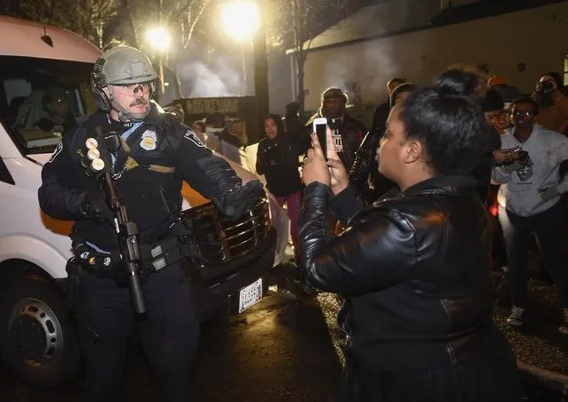 A police officer tells a women to back up as she photographs him in front of a north Minneapolis police precinct during a protest in response of Sunday's shooting death of Jamar Clark by police officers in Minneapolis, Minnesota, November 18, 2015. (Photo by Craig Lassig/Reuters)