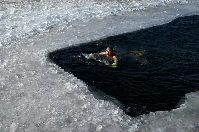 An ice swimmer swims in a frozen lake on a cold winter day in Beijing on January 6, 2021. (Photo by Wang Zhao/AFP Photo)