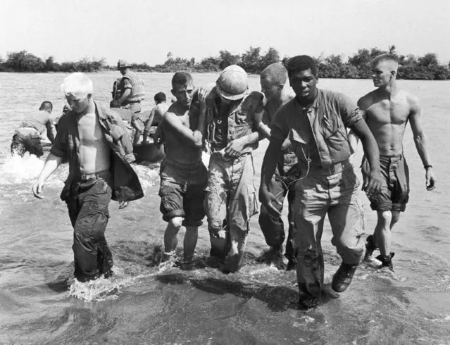 A wounded Marine is comforted upon arriving at this evacuation point at Dai Do, Vietnam on May 7, 1968. The Marine was wounded while attacking the North Vietnamese held village of Dai Do near the DMZ. The artillery-supported North Vietnamese pushed back the Marines. (Photo by Eddie Adams/AP Photo)