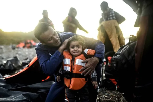 A Greek doctor tries to comfort a child after migrants and refugees arrived on the shores of the Greek island of Lesbos after crossing the Aegean Sea from Turkey on November 12, 2015. European Union and African leaders on November 12 approved a 1.8-billion-euro action plan they hope will help stem an unprecedented and politically explosive flow of migrants across the Mediterranean. (Photo by Bulent Kilic/AFP Photo)