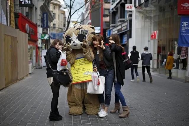 Japanese tourists take a selfie with a promoter of a cat cafe at Myeongdong shopping district in Seoul, South Korea, November 24, 2015. (Photo by Kim Hong-Ji/Reuters)