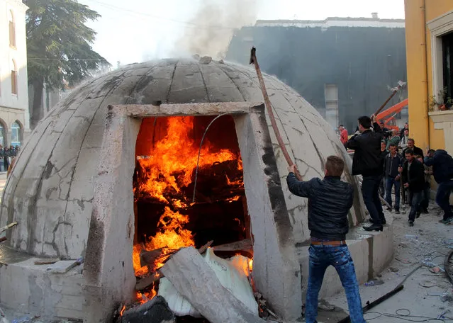 Opposition protesters destroy a bunker installed as an artwork near the Interior ministry  during a rally organized by the opposition Democratic Party to demand the resignation of the government, in Tirana, on December 8, 2015, on the day that marks the 25th anniversary of the student protests that led to the toppling of the last communist regime in Europe in 1990. 
(Photo by Gent Shkullaku/AFP Photo)