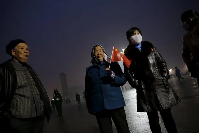 People gather before sunrise at Tiananmen Square for a flag-raising ceremony amid heavy smog, after the city issued its first ever "red alert" for air pollution, in Beijing December 9, 2015. (Photo by Damir Sagolj/Reuters)