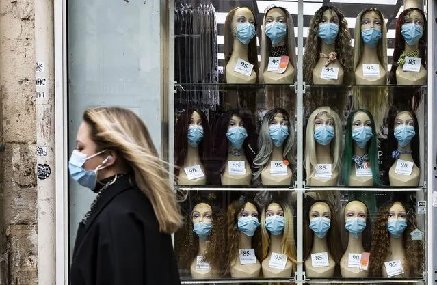 A woman wearing a protective face mask walks past a shop window displaying mannequin heads with masks, in Paris, France, 28 October 2020. France is in the midst of a second wave of the COVID-19 coronavirus pandemic, recording around 50,000 daily new cases. France has currently placed 45 million of its citizen across several 'departments' (counties) under a night-time curfew prohibiting leaving one's house between 9pm and 6am. French President Emmanuel Macron is set to announce in a televised statement on 28 October new measures to battle the rise in Covid-19 cases – with many speculating a return to lockdown, dubbed “reconfinement”. (Photo by Ian Langsdon/EPA/EFE)