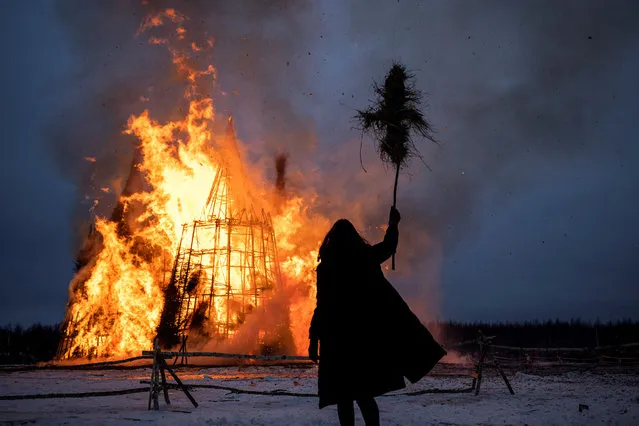 This picture taken on March 13, 2021, shows a spectator watching the burning wooden structure “Corona Tower” created by Russian artist Nikolay Polissky during celebrations of Maslenitsa, the eastern Slavic Shrovetide in the village of Nikola-Lenivets. Shrovetide or Maslenitsa is an ancient farewell ceremony to winter, traditionally celebrated in Belarus, Russia and Ukraine and involves the burning of a large effigy. (Photo by Dimitar Dilkoff/AFP Photo)