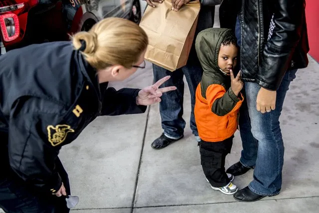 Flint Police Capt. Leigh Golden, left, holds up two fingers as to mimic Israel Altheimer, 2, as he tells her his age on Thursday, December 10, 2015 at the Flint Farmers' Market in Flint, Mich This is the second year The Flint Police Department teamed up with the Salvation Army of Flint and Genesee County to help raise donations for the Red Kettle Drive. (Photo by Jake May/The Flint Journal-MLive.com via AP Photo)