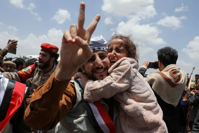 A freed prisoner gestures while holding a child after arriving at Sanaa Airport on an International Committee of the Red Cross (ICRC)-chartered plane, amid a prisoner swap between two sides in the Yemen conflict, in Sanaa, Yemen on April 14, 2023. (Photo by Khaled Abdullah/Reuters)