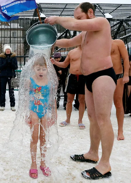 Grigory Broverman, a member of a local winter swimmers club, pours a bucket of cold water over his 7-year-old daughter Liza during a celebration of Polar Bear Day at the Royev Ruchey zoo, with the air temperature at about minus 5 degrees Celsius (23 degrees Fahrenheit), in Krasnoyarsk, Russia, November 27, 2016. (Photo by Ilya Naymushin/Reuters)