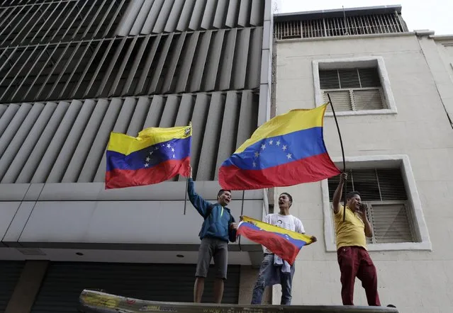 Supporters of Venezuela's opposition hold national flags as they stand some streets away from the building housing the National Assembly in Caracas, January 5, 2016. (Photo by Marco Bello/Reuters)