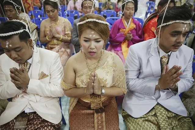 Brides and grooms pray before stepping into a pink coffin during their wedding ceremony at Wat Takien temple in Nonthaburi province, on the outskirts of Bangkok February 14, 2015. (Photo by Damir Sagolj/Reuters)