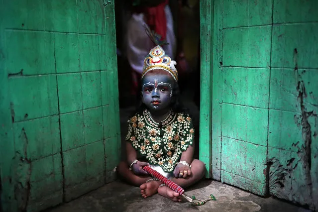 A child sits on the doorstep, who dressed as Lord Krishna during Janmashtami festival, which marks the birth anniversary of Lord Krishna in Dhaka, Bangladesh, September 2, 2018. (Photo by Mohammad Ponir Hossain/Reuters)