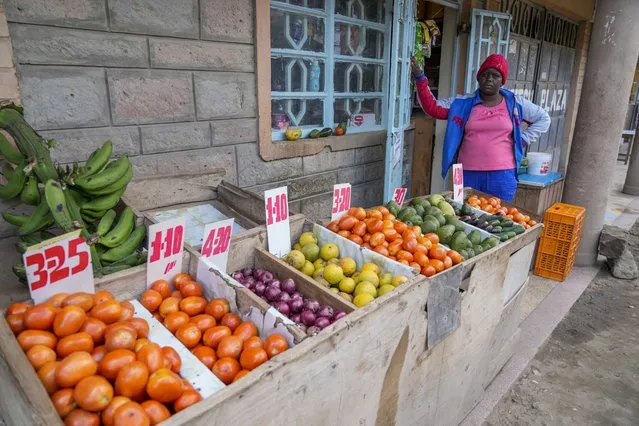 The owner of a small-scale shop selling vegetables stands by her produce in Kitengela, on the outskirts of the capital Nairobi, Kenya, Monday, April 17, 2023. In Kenya, drought added to food shortages and high prices arising from the impact of war in Ukraine, and costs have stayed stubbornly high ever since. (Photo by Khalil Senosi/AP Photo)