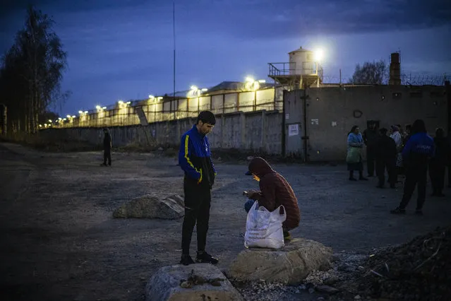 Migrant workers stand by the barbed wire fence of the IK-3 penal colony where jailed Kremlin critic Alexei Navalny was reportedly transferred in the city of Vladimir on April 19, 2021. Russia's penitentiary service said on April 19, 2021, it was transferring ailing Kremlin critic Alexei Navalny to a prison hospital, as the EU warned it would hold Moscow responsible for the state of his health. The United States on Sunday threatened Russia with “consequences” if President Vladimir Putin's major domestic opponent – who launched a hunger strike three weeks ago – dies in jail, with Navalny's private doctors warning at the weekend he could pass away at “any minute”. (Photo by Dimitar Dilkoff/AFP Photo)