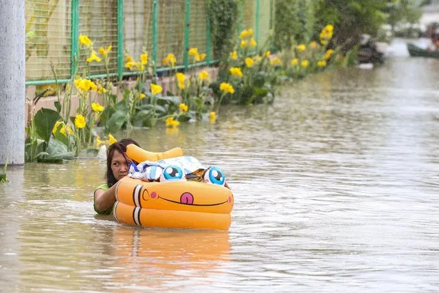A woman wades through floodwaters left by torrential rains of Typhoon Doksuri in Calumpit, Bulacan province on July 29, 2023. (Photo by Earvin Perias/AFP Photo)