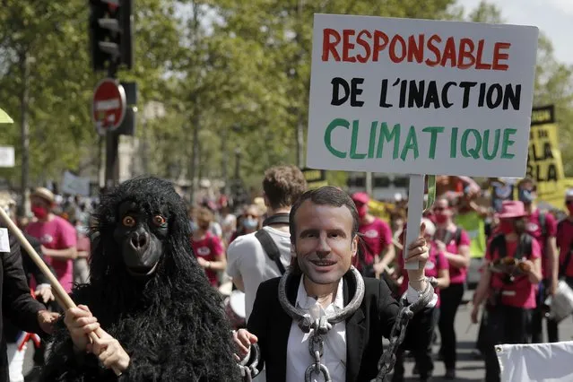 A protester wearing a mask depicting French President Emmanuel Macron holds a bord reading « Liable for climate inaction » during a rally against the climate change in Paris, Sunday, May 9, 2021. Thousands of French demonstrators took to the streets of Paris and other cities on Sunday to call for more ambitious measures to fight against climate change. (Photo by Christophe Ena/AP Photo)