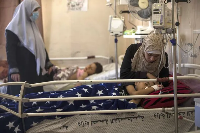The mother of Yazan Al-zaharna, 9, comforts him as he rests at the Shifa hospital in Gaza City, Thursday, May 13, 2021, where he is receiving treatment for wounds caused by a May 10 Israeli strike that hit a nearby his family house in town of Jabaliya. Just weeks ago, the Gaza Strip’s feeble health care system was struggling with a runaway surge of coronavirus cases. Now doctors across the crowded coastal enclave are trying to keep up with a very different crisis: blast and shrapnel wounds, cuts and amputations. (Photo by Khalil Hamra/AP Photo)