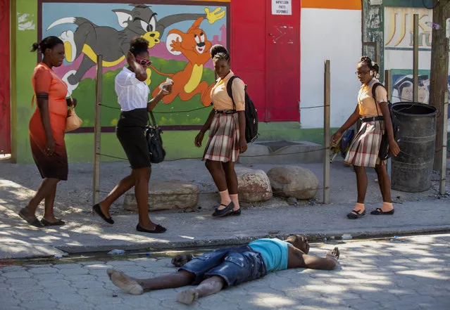 Pedestrians walk past a body of a prison inmate lying on a street near the Croix-des-Bouquets Civil Prison after an attempted breakout, in Port-au-Prince, Haiti, Thursday, February 25, 2021. (Photo by Dieu Nalio Chery/AP Photo)