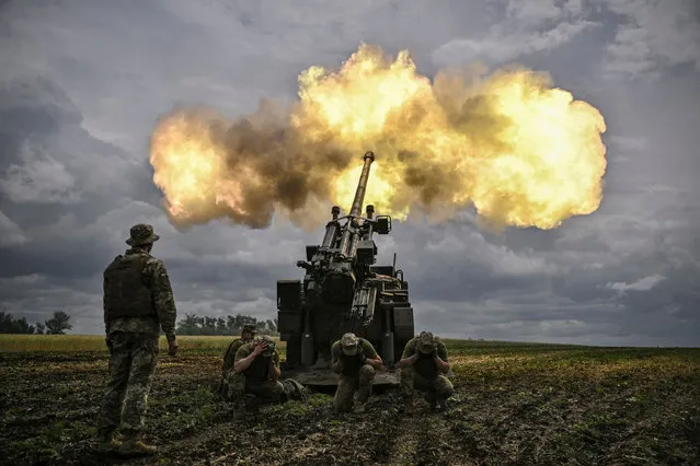 Ukrainian servicemen fire with a French self-propelled 155 mm/52-calibre gun Caesar towards Russian positions at a front line in the eastern Ukrainian region of Donbas on June 15, 2022. Ukraine pleaded with Western governments on June 15, 2022 to decide quickly on sending heavy weapons to shore up its faltering defences, as Russia said it would evacuate civilians from a frontline chemical plant. (Photo by Aris Messinis/AFP Photo)