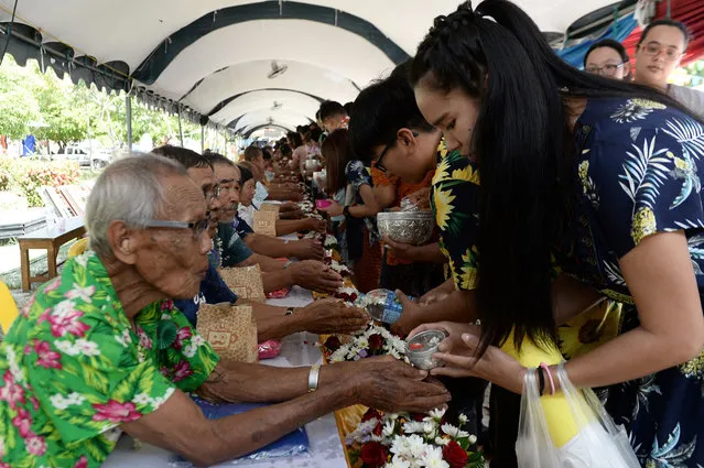 People (R) pour water on the hands of elders (L) to ask for blessings and as a sign of respect, during ceremonies to celebrate Songkran, the Thai New Year, in Narathiwat on April 13, 2018. (Photo by Madaree Tohlala/AFP Photo)