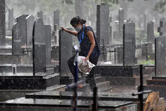 Akshaya, 22, a law student and a volunteer, walks to take shelter from rain after carrying the body of a person, who died from the coronavirus disease (COVID-19), for burial at a cemetery in Bengaluru, India, May 18, 2021. (Photo by Samuel Rajkumar/Reuters)