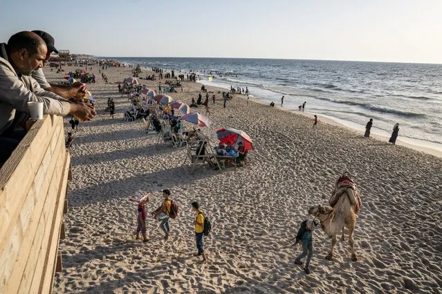 A man offer camel rides to customers on the shores of the Mediterranean Sea, as life begins to return to a semblance of normal, days after the end of an 11-day war between Gaza's Hamas rulers and Israel, Tuesday, May 25, 2021, in Gaza City. (Photo by John Minchillo/AP Photo)