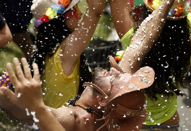 A man welcomes blasts of artificial snow sprayed on revelers as they dance at the Bicho Maluco Beleza street carnival block party in Sao Paulo, Brazil, Saturday, January 30, 2016. Brazil's over-the-top Carnival is the highlight of the year for many local residents. Hundreds of thousands of merrymakers are taking to the streets in hundreds of open-air “bloco” parties, leading up to Carnival's official February 5th opening. (Photo by Andre Penner/AP Photo)