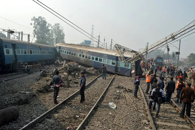 Rescuers and railway officials stand next to damaged coaches of a passenger train after it derailed near Kanpur in the northern state of Uttar Pradesh, India, December 28, 2016. (Photo by Reuters/Stringer)
